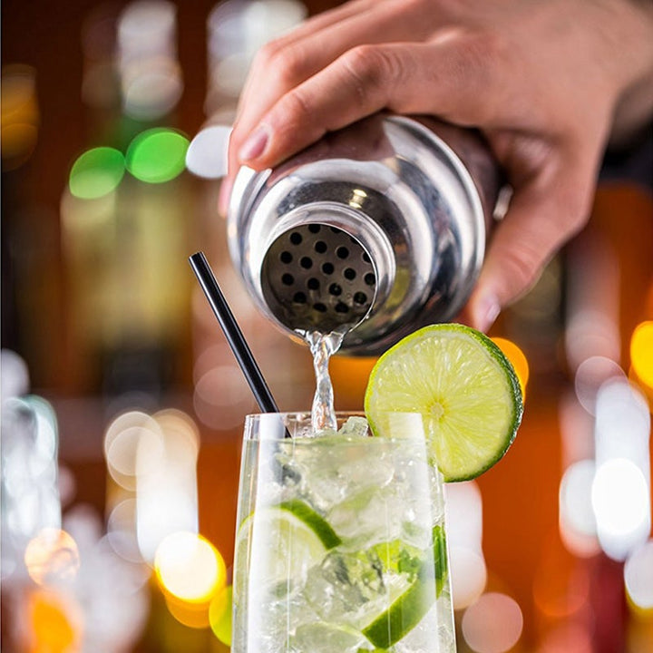 Complete cocktailshaker set met roestvrijstalen accessoires en houten standaard, ideaal voor thuisbars en bartenders.
