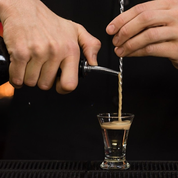 Complete cocktailshaker set met roestvrijstalen accessoires en houten standaard, ideaal voor thuisbars en bartenders.