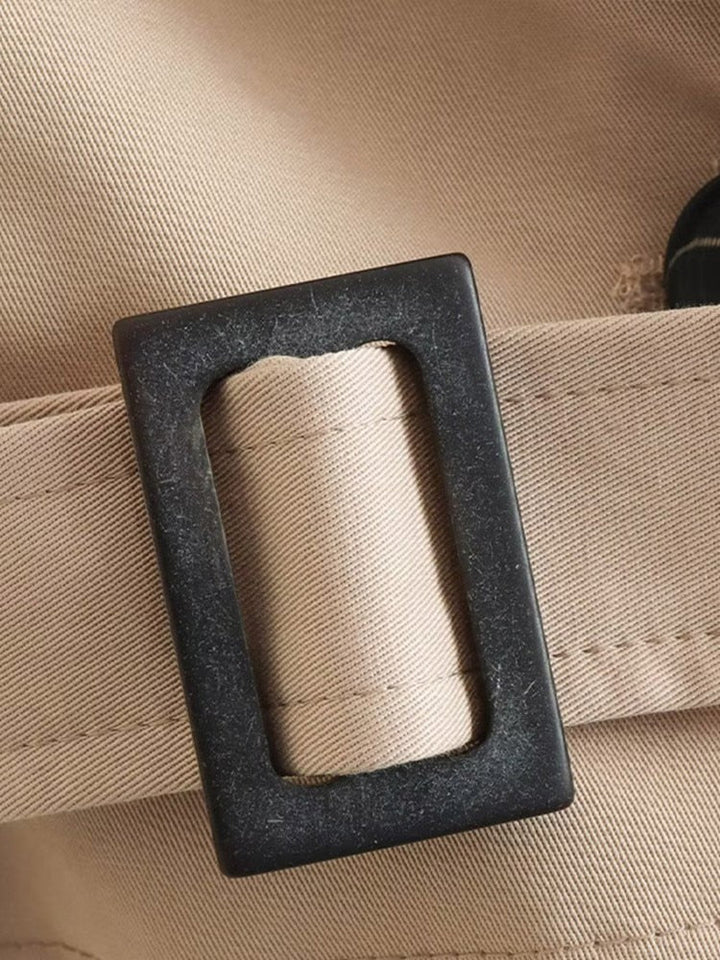 "Cropped beige trenchcoat voor dames, stijlvolle dubbele rij knopen en verstelbare manchetten, elegant en modern ontwerp."