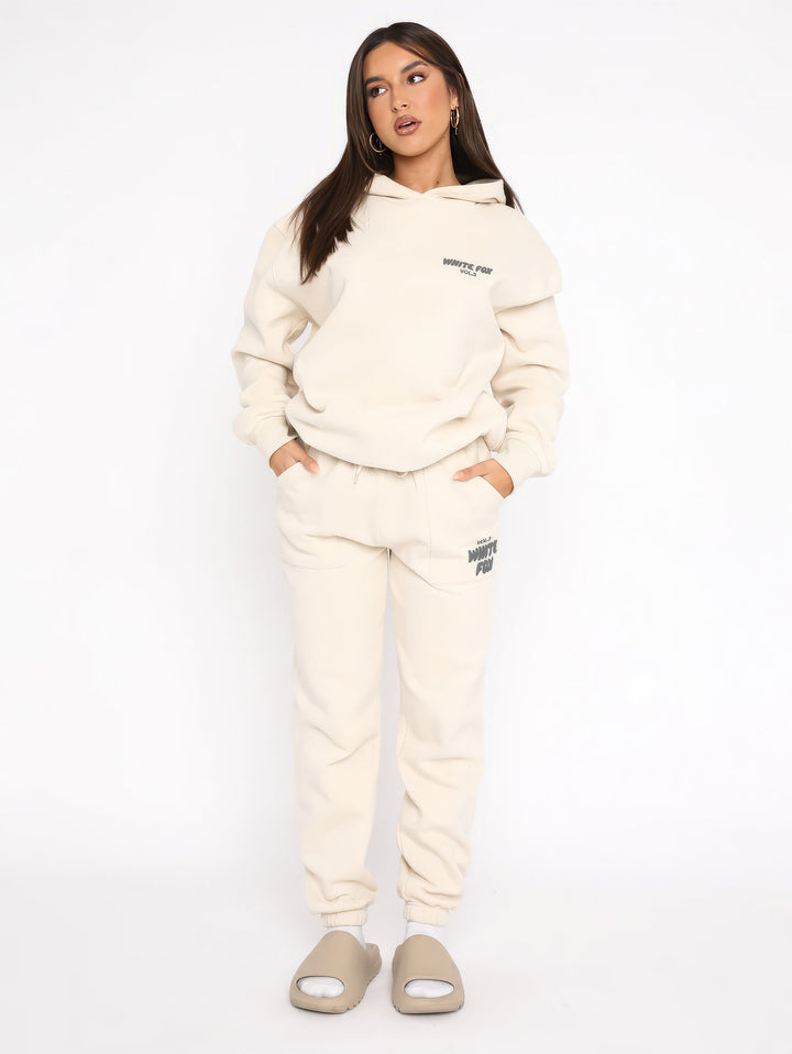 "Dames trainingspak met oversized pasvorm, wit, elastische ribboorden, trendy puffprint logo en fleecestof."