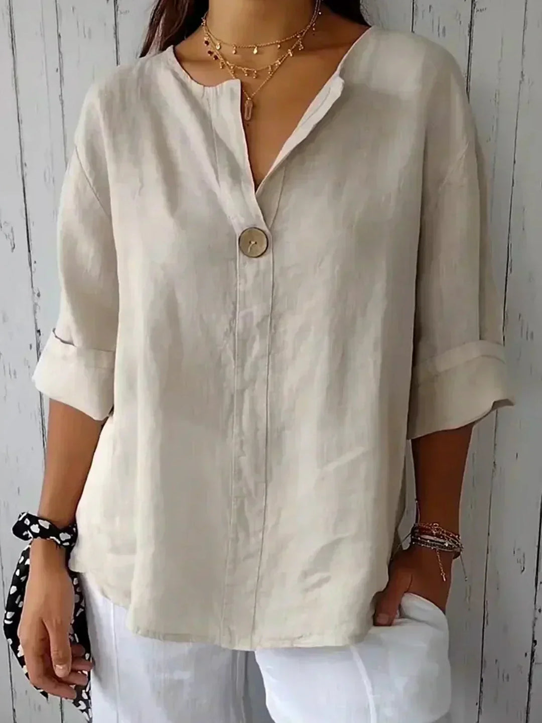 "Dames zomerblouse met V-hals en knoopdetail, luchtige stof, verfijnde stijl, perfect voor warme dagen in een losse pasvorm."