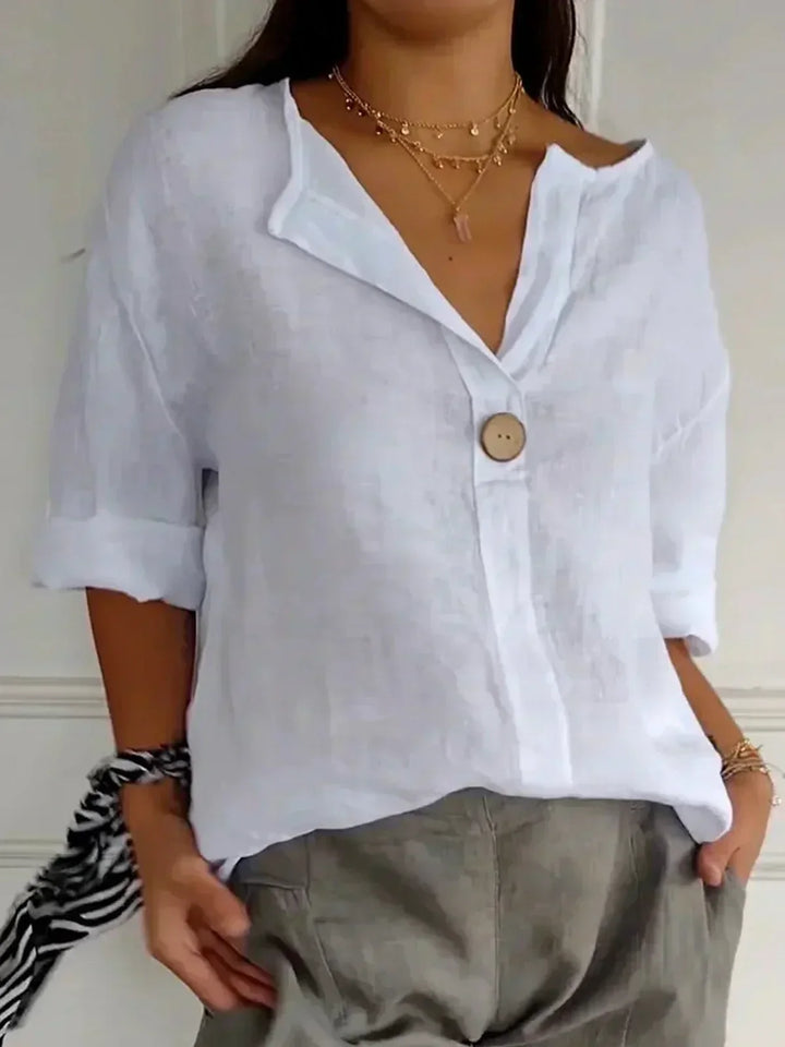 "Dames zomerblouse met V-hals en knoopdetail, luchtige stof, verfijnde stijl, perfect voor warme dagen in een losse pasvorm."