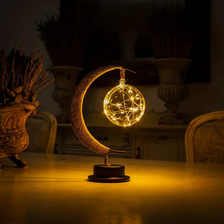 "Dromerige maanlamp van borosilicaatglas met zachte LED-gloed, creëert een betoverende sfeer op tafel."