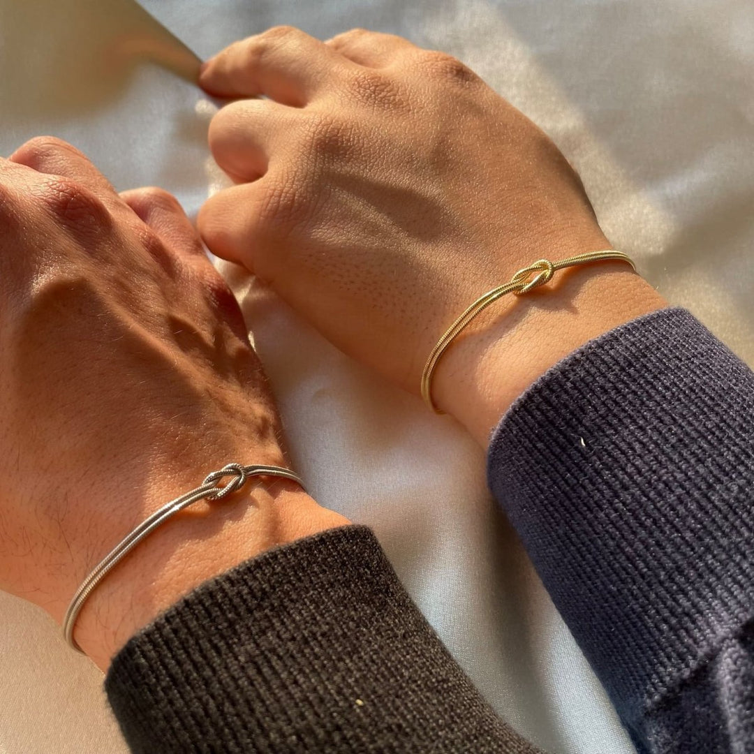 "Elegant damesarmband met liefdesknoopdesign, verstelbaar, minimalistisch en stijlvol in goud of zilverkleur."