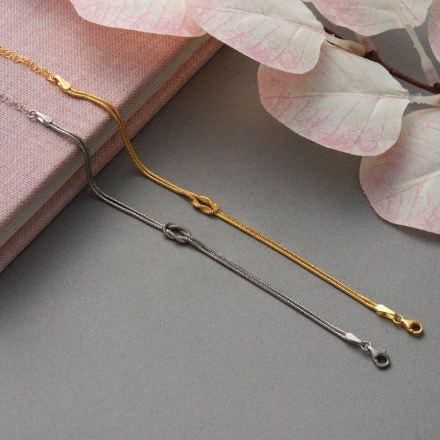 "Elegant damesarmband met liefdesknoopdesign, verstelbaar, minimalistisch en stijlvol in goud of zilverkleur."