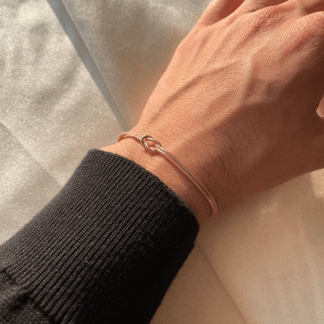 "Elegant damesarmband met liefdesknoopdesign, verstelbaar, minimalistisch en stijlvol in goud of zilverkleur."