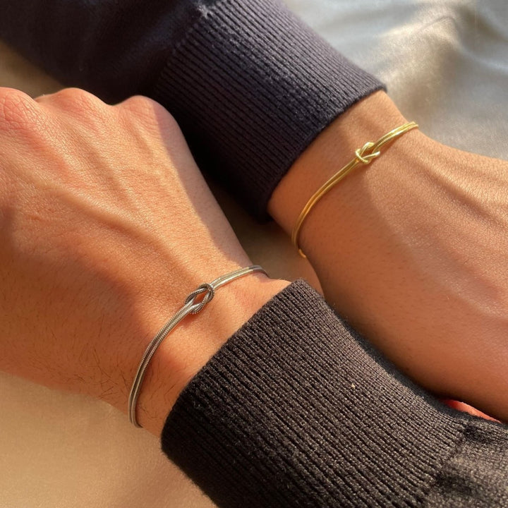 "Elegant damesarmband met liefdesknoopdesign, verstelbaar, minimalistisch en stijlvol in goud of zilverkleur."