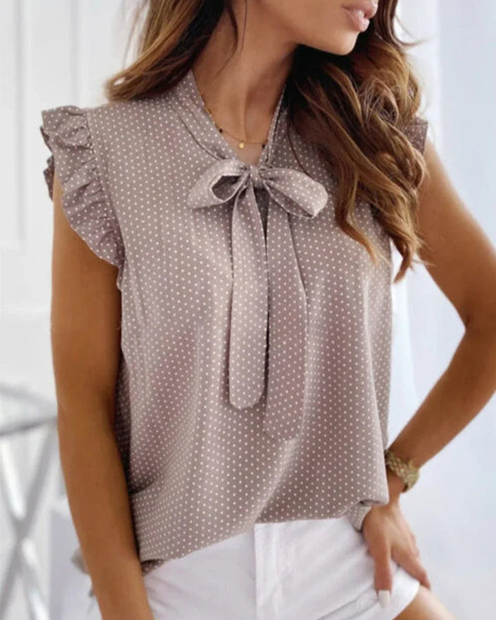 "Elegante Brianna damesblouse met polkadots, strikdetail en ruffles; luchtige zomertop voor veelzijdige stijl."