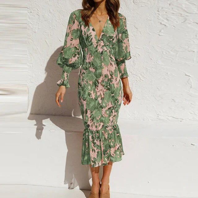 "Elegante lichtgroene midi-jurk met bloemenpatroon, V-hals en trompetmouwen, perfect voor lente- en zomerevenementen."