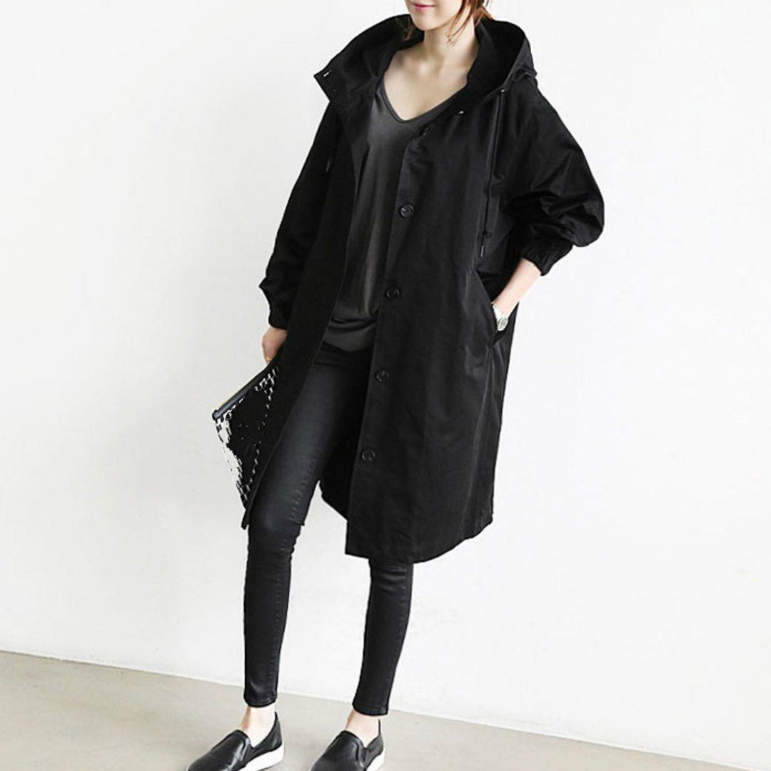 "Esmée lange dames trenchcoat zwart, elegant, wind- en waterdicht met capuchon en verstelbare taille voor perfecte pasvorm."