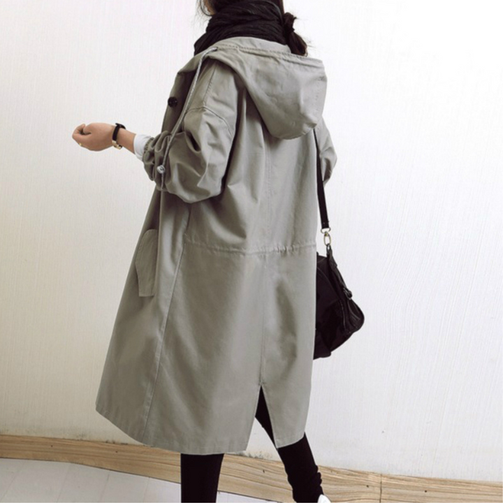 "Esmée lange dames trenchcoat zwart, elegant, wind- en waterdicht met capuchon en verstelbare taille voor perfecte pasvorm."