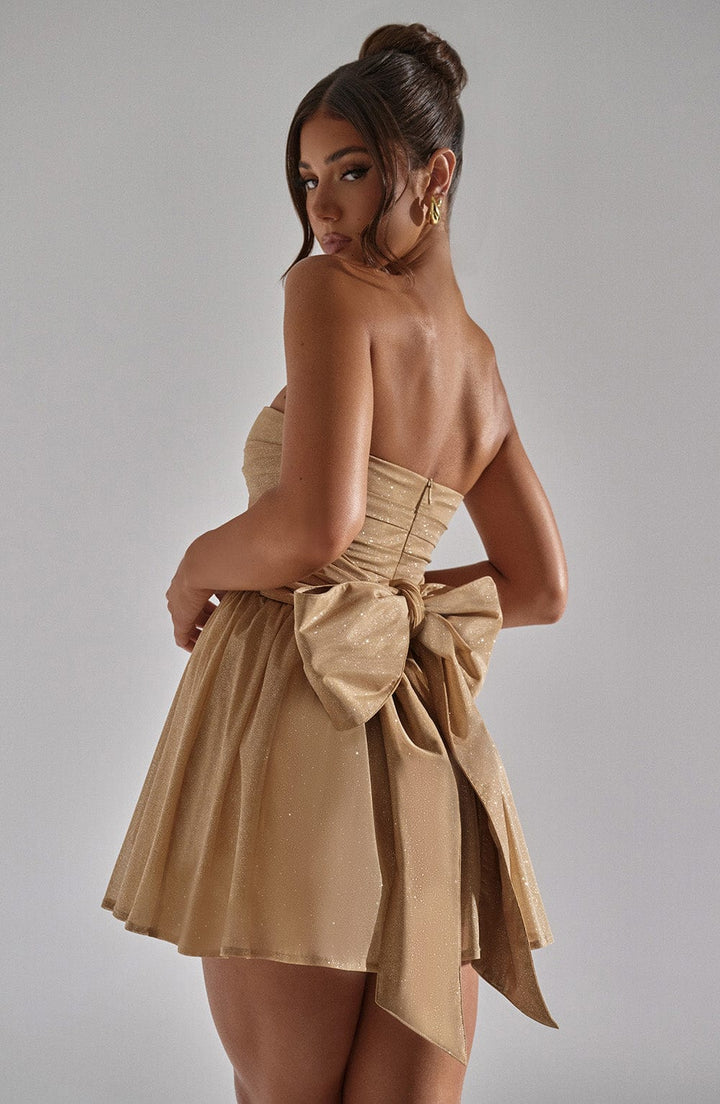 "Glimmende strapless mini-jurk met gouden glitters, flared rok en oversized strik - perfecte partyjurk voor dames."