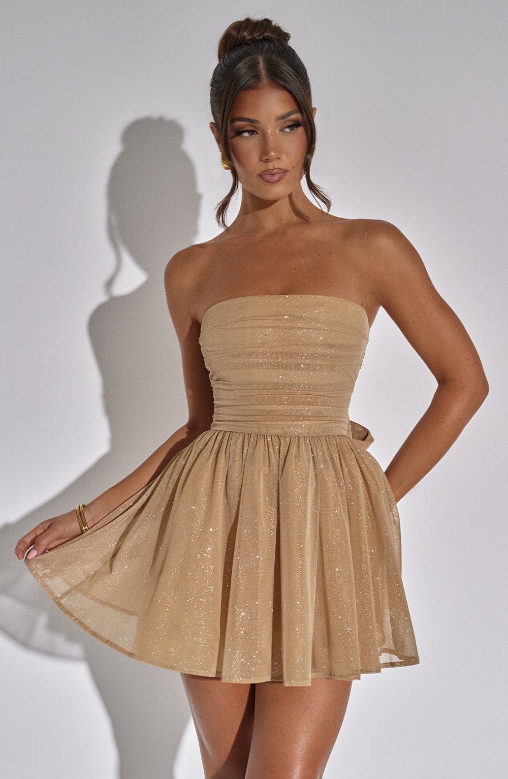 "Glimmende strapless mini-jurk met gouden glitters, flared rok en oversized strik - perfecte partyjurk voor dames."