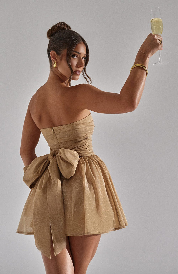 "Glimmende strapless mini-jurk met gouden glitters, flared rok en oversized strik - perfecte partyjurk voor dames."