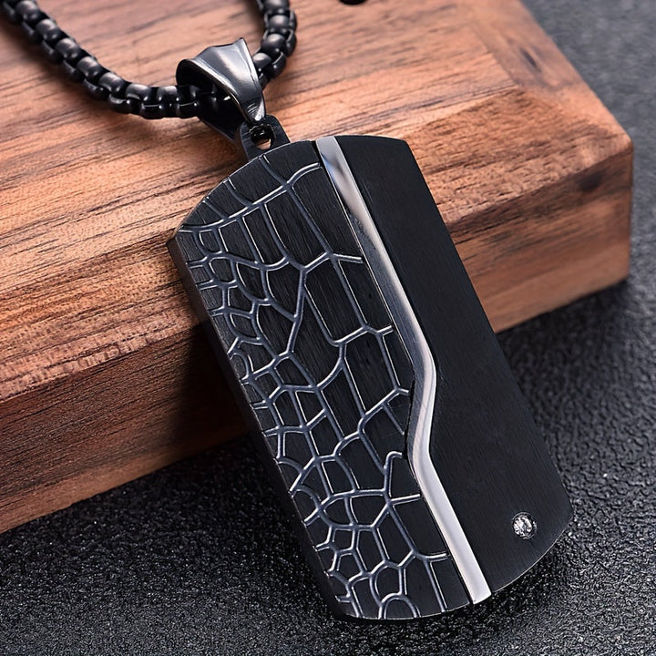 "Heren ketting met zwarte vintage hanger van roestvrij staal, stijlvol gebarsten design, stoere en duurzame uitstraling."