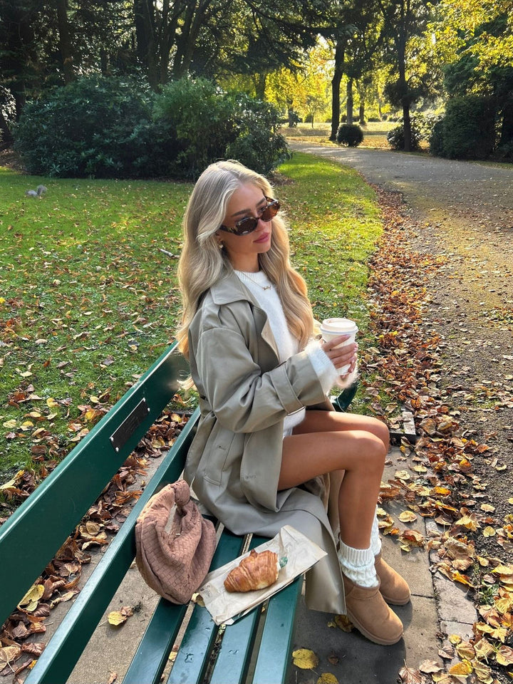 "Lange dames trenchcoat met klassieke knoopsluiting, beige kleur, relaxed fit, elegante uitstraling, verstelbare ceintuur."
