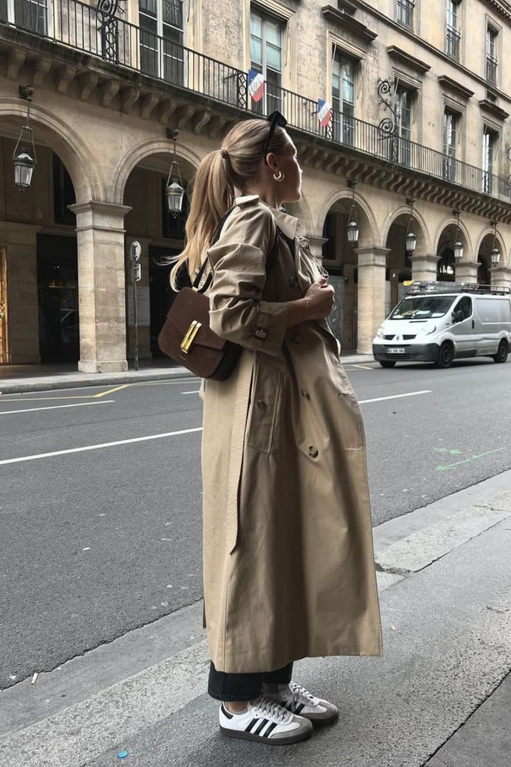 "Lange dames trenchcoat met klassieke knoopsluiting, beige kleur, relaxed fit, elegante uitstraling, verstelbare ceintuur."