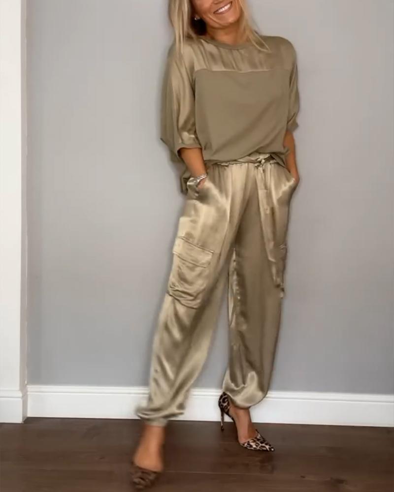 "Luxe satijnen damespak, tweedelig; elegante grijze top met driekwartsmouwen en bijpassende soepele broek."