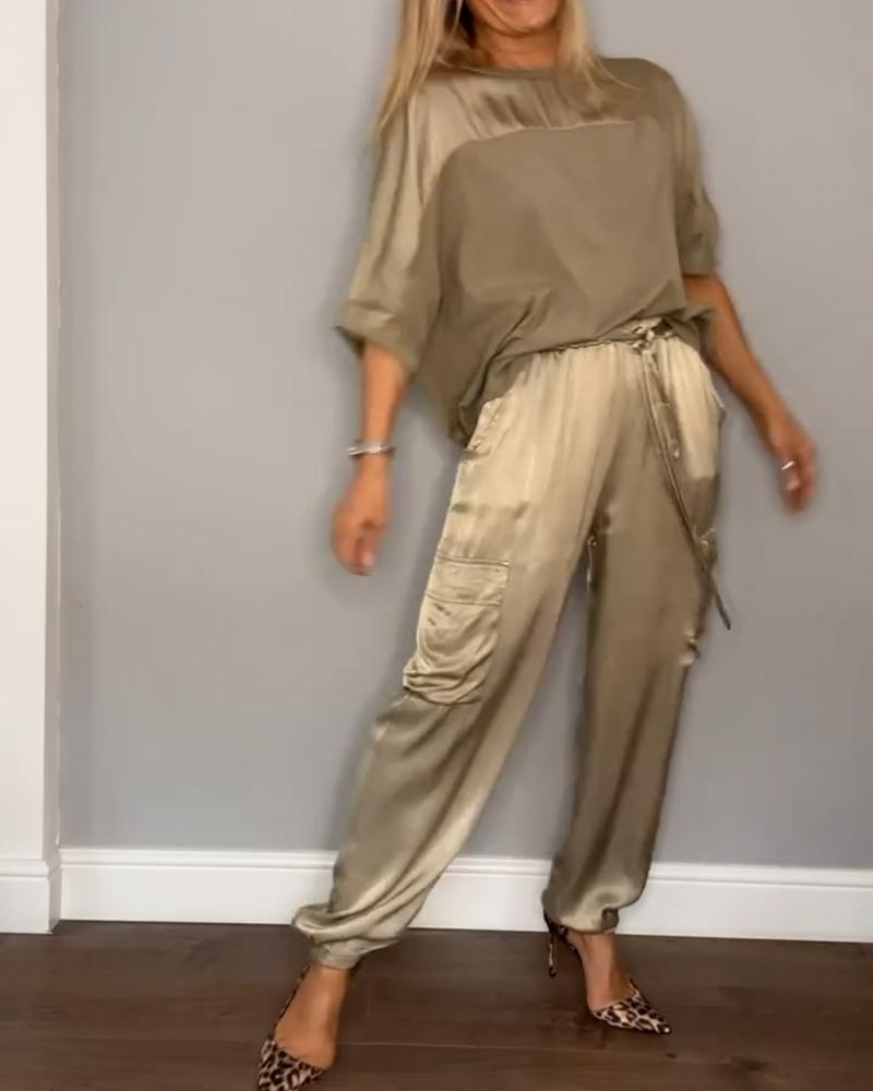 "Luxe satijnen damespak, tweedelig; elegante grijze top met driekwartsmouwen en bijpassende soepele broek."
