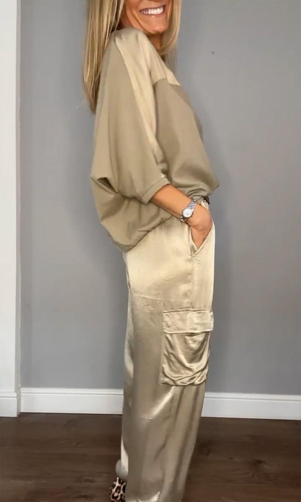 "Luxe satijnen damespak, tweedelig; elegante grijze top met driekwartsmouwen en bijpassende soepele broek."