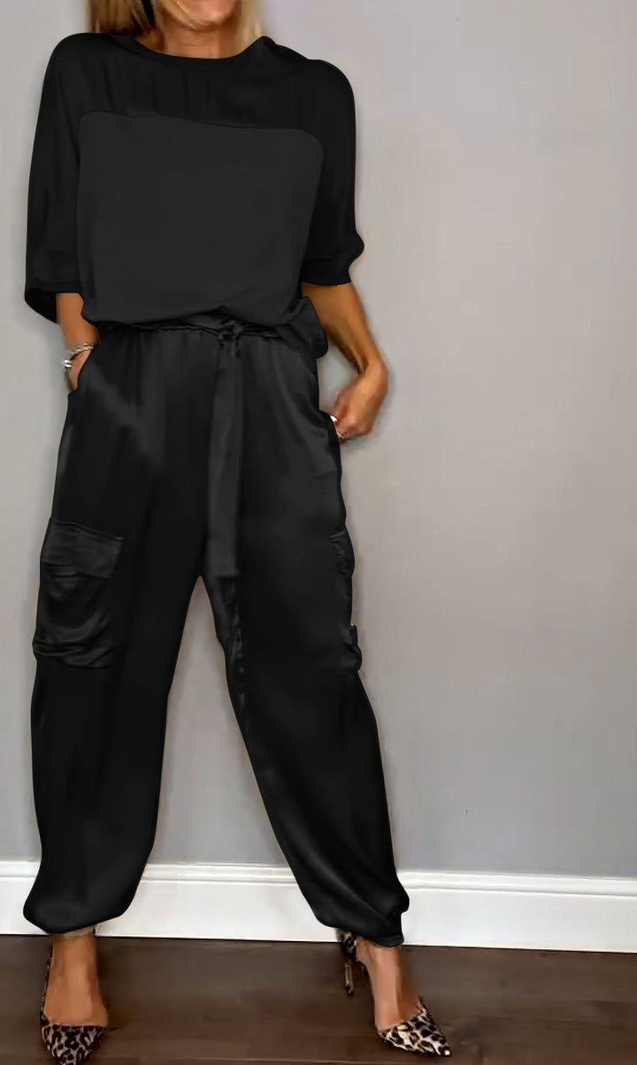 "Luxe satijnen damespak, tweedelig; elegante grijze top met driekwartsmouwen en bijpassende soepele broek."