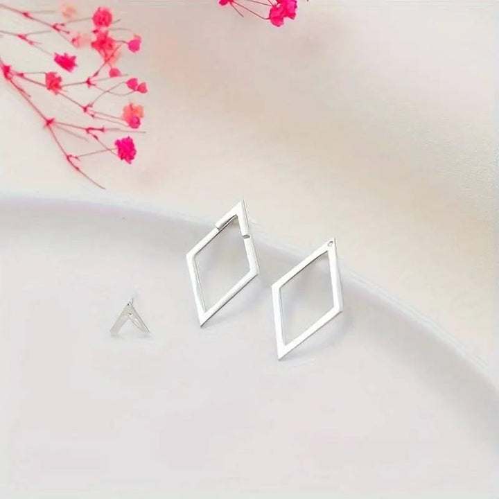 "Minimalistische geometrische oorbellen in goud en zilver met speelse diamant- en pijlvorm, luxe glans en elegante uitstralin