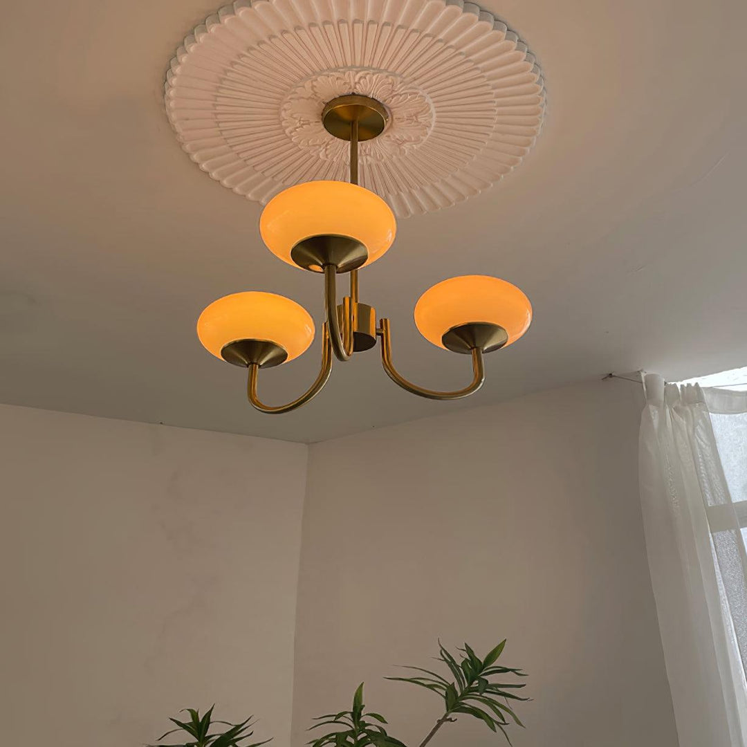 "Moderne kroonluchter met gouden afwerking en roze glazen kappen, geschikt voor LED verlichting in eigentijds interieur."