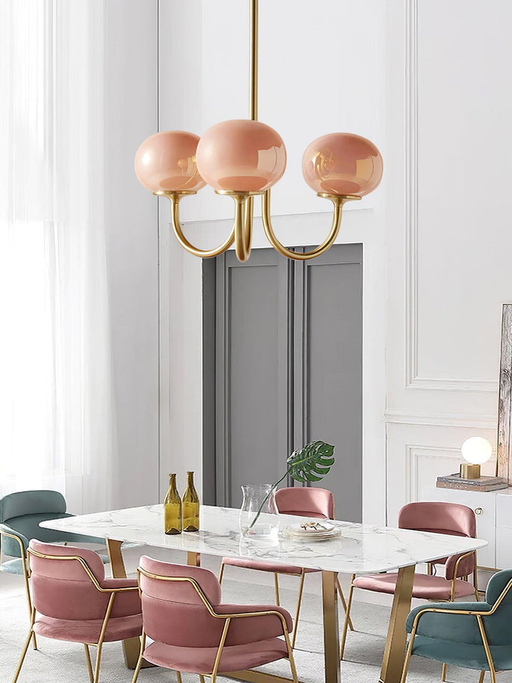 "Moderne kroonluchter met gouden afwerking en roze glazen kappen, geschikt voor LED verlichting in eigentijds interieur."