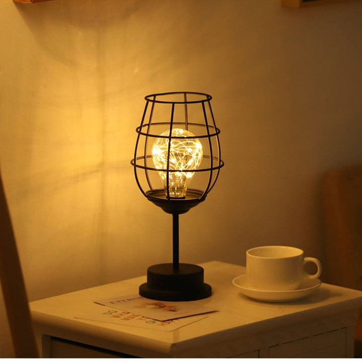 "Rustieke tafellamp met industrieel ontwerp, straalt warm licht uit, ideaal voor sfeerverlichting in moderne interieurs."