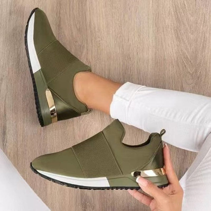 "Stijlvolle beige en rode damessneakers met gouden accenten, ademend bovenwerk en comfortabele pasvorm op houten vloer."