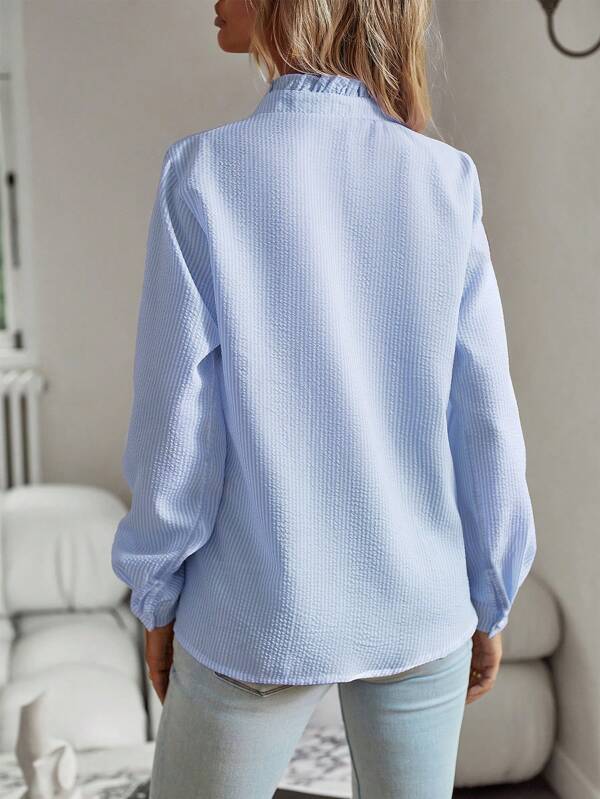 "Vrouw in trendy blouse met subtiele streepjes, ruches, en elegante knoopsluiting voor veelzijdige damesmode"