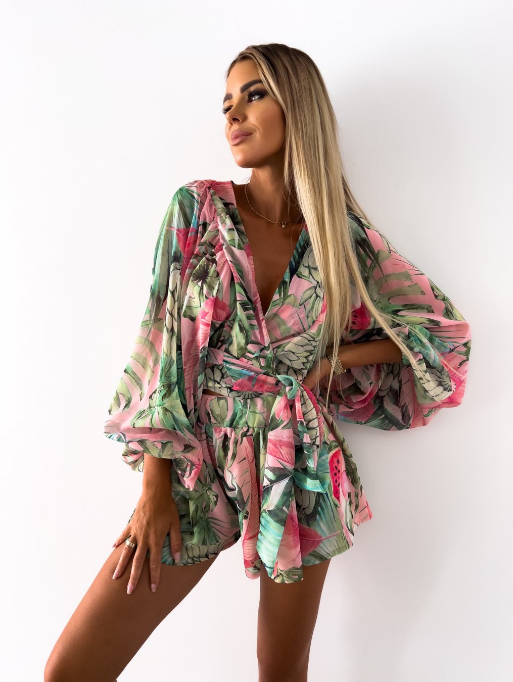 "Zomerse playsuit met V-hals, fruit- en bladmotieven, kleurrijke tropische print, accentueert silhouet en biedt comfort."