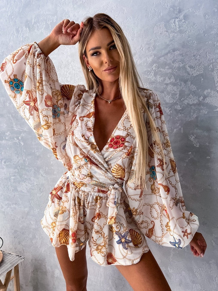 "Zomerse playsuit met V-hals, fruit- en bladmotieven, kleurrijke tropische print, accentueert silhouet en biedt comfort."